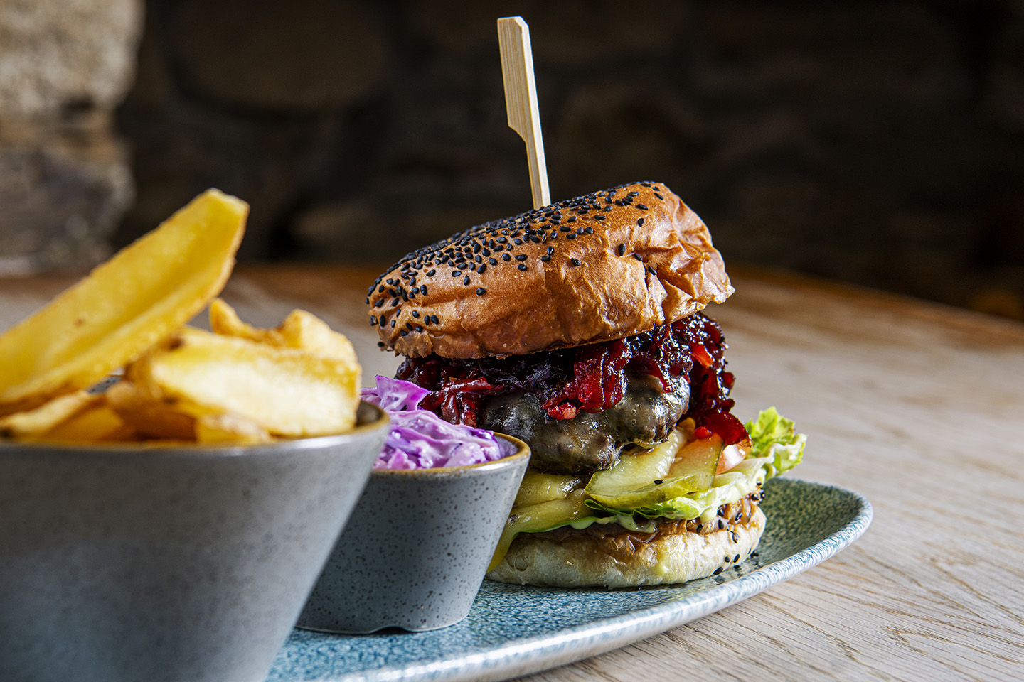 Image shows a huge burger in a bun with fries and slaw on the side