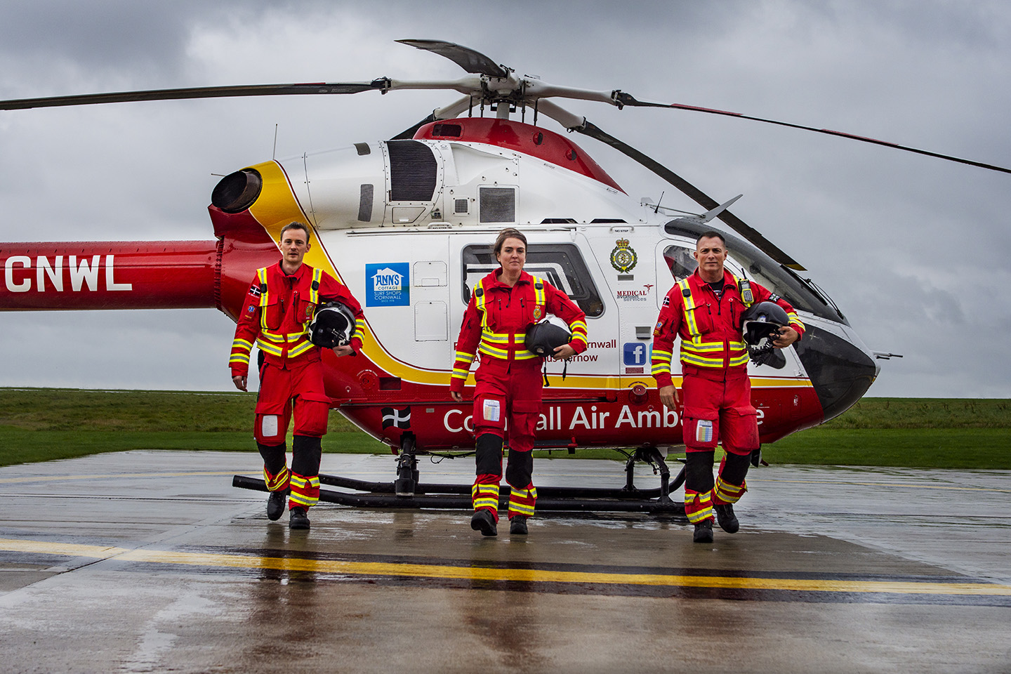 Three Cornwall Air Ambulance paramedics walking away from the helicopter on the landing pad