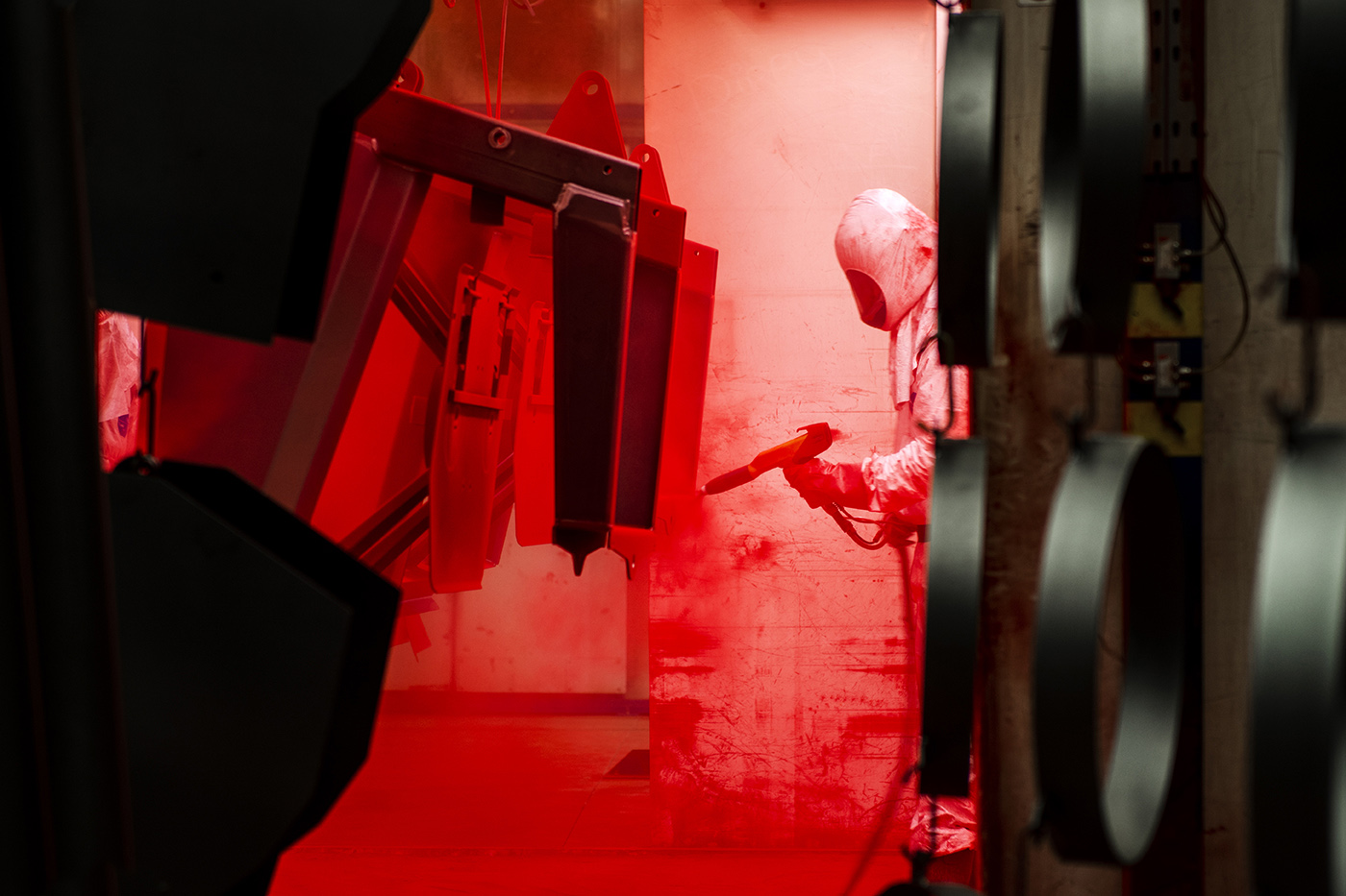 A worker at a manufacturing plant, powder coating metal parts for agricultural equipment