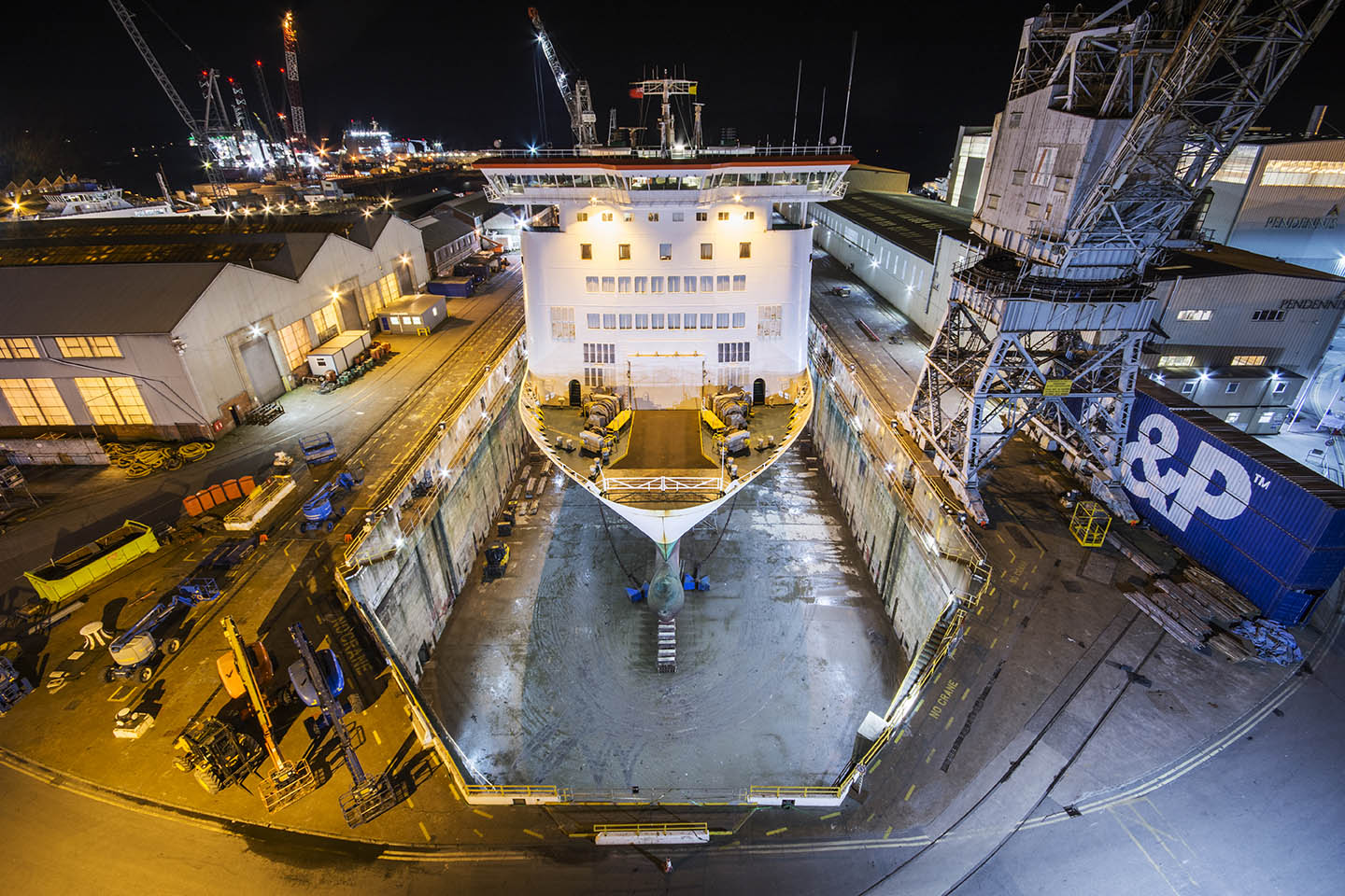 View of Pendennis Shipyard in Falmouth at night, illuminated crane and large structures