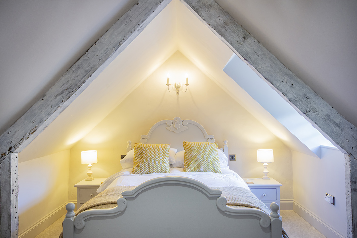 attic bedroom with king sized bed and lamps either side