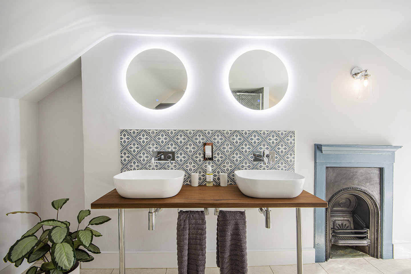 one of the bathrooms featuring a cast iron fireplace and double sinks and mirrors