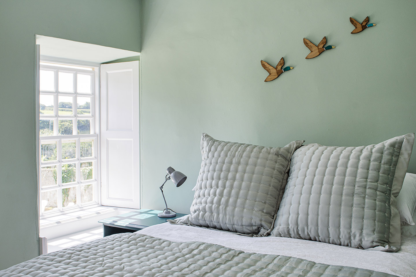 bedroom decorated in soft pale green with flying ducks on the wall