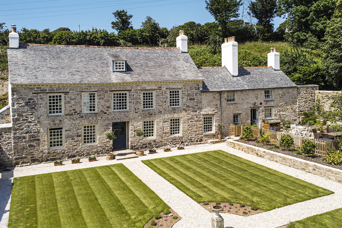 drone shot of the front of Cusgarne Manor, a grade 2 listed farmhouse with striped lawn at the front