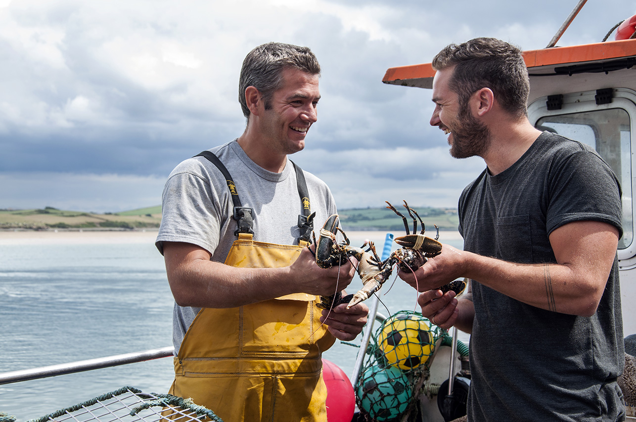 Fisherman Johnny Murt and chef Rick Toogood share a laugh over a lobster on a fishing boat in Padstow