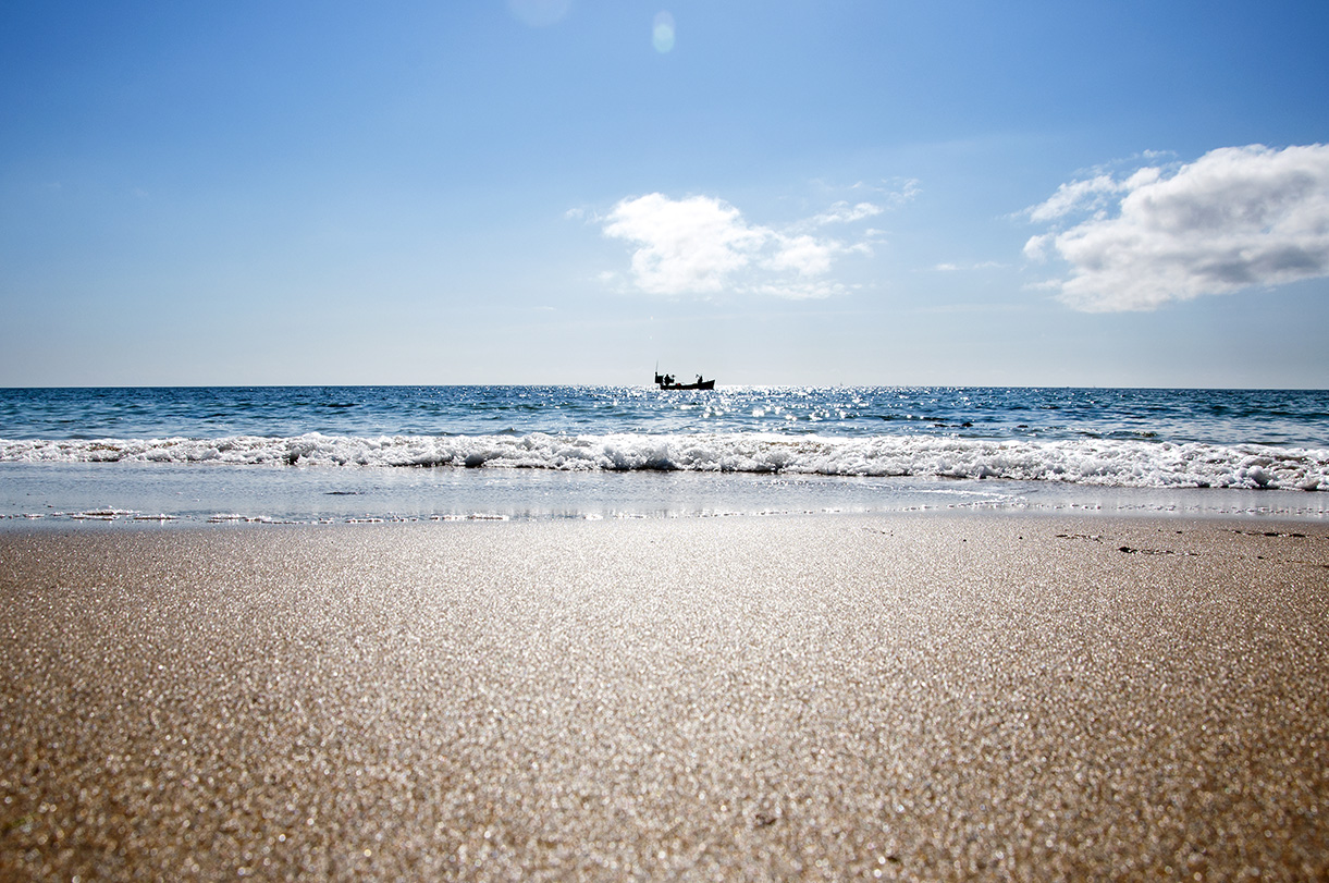 View of a fishing boat on the horizon on a bright sunny summers day at Towan beach on the Roseland Peninsula, Cornwall 