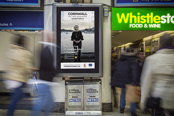 A JC Decaux digital billboard at a busy London station with a portrait of Fiona Campbell-Howes on it