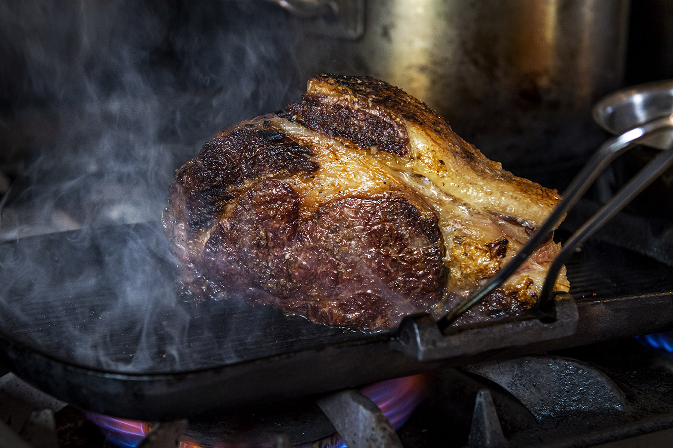 A large cut of beef sizzling on the grill at the Lemon Street Longstore