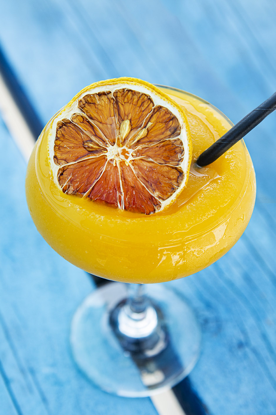 A close up of a frozen passion fruit cocktail on a blue wooden table