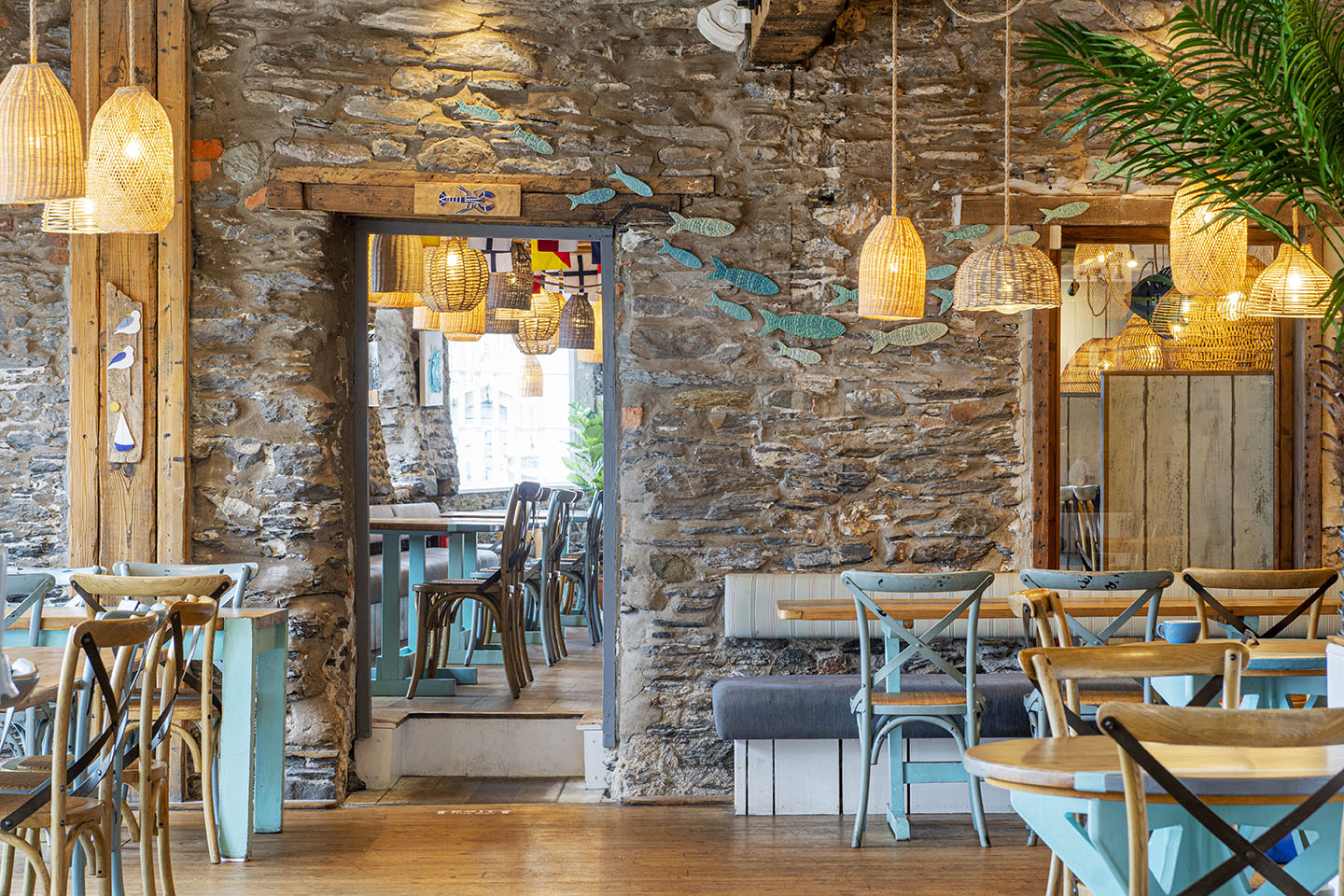 Interior of the Sharksfin restaurant in Mevagissey with straw lampshades and old stone wall