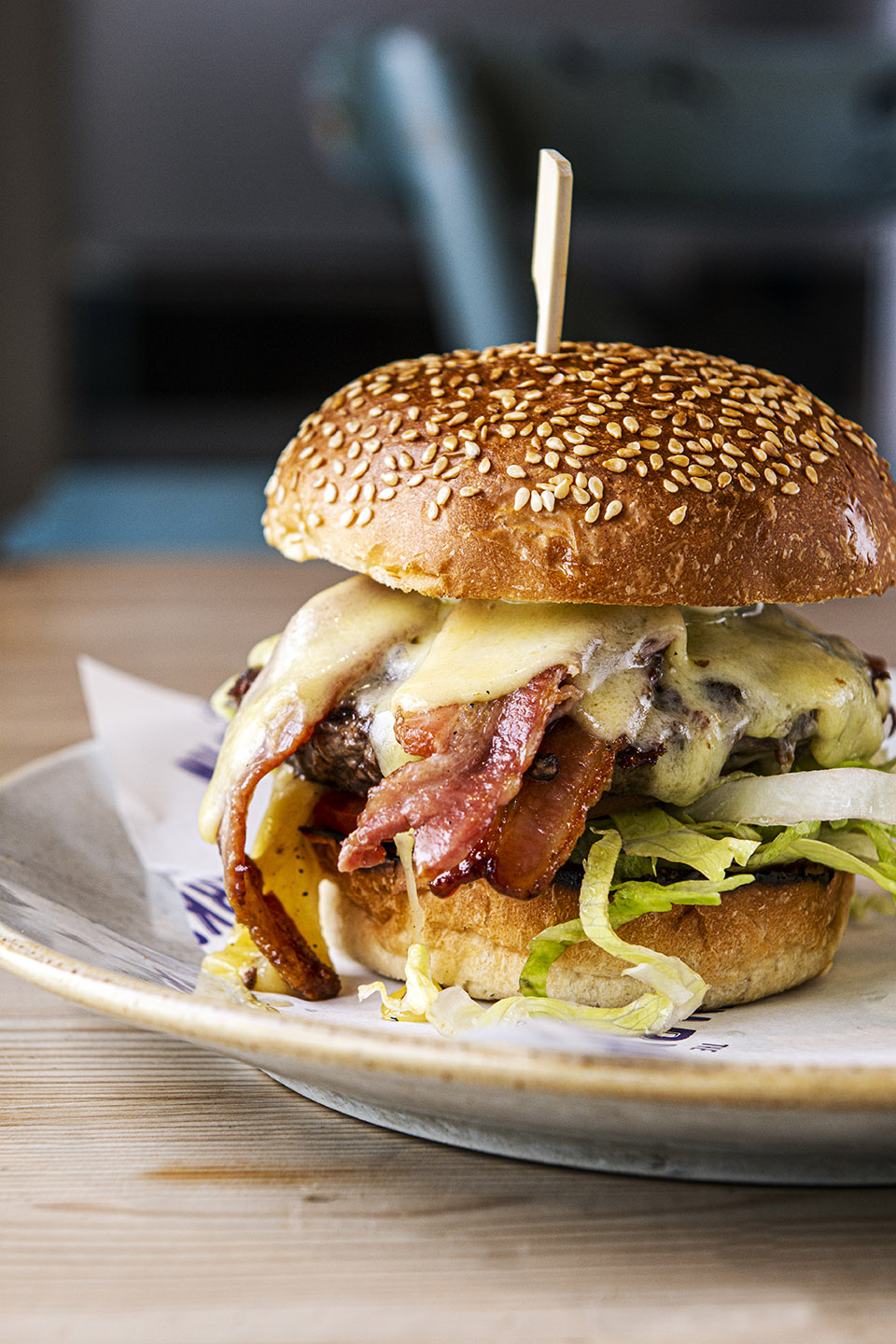 Close up of a burger on a plate with melting cheese and bacon in it