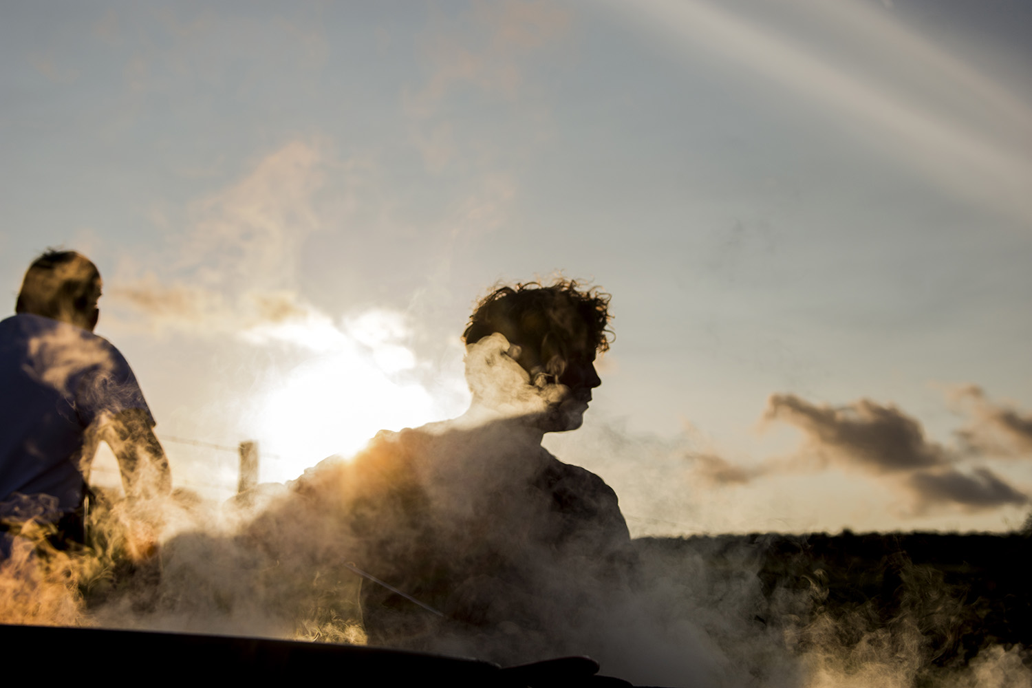 Chefs at the Hidden Hut cooking at sunset with steam from the paella pans rising in the foreground